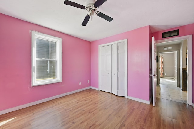 unfurnished bedroom featuring baseboards, wood finished floors, visible vents, and a closet