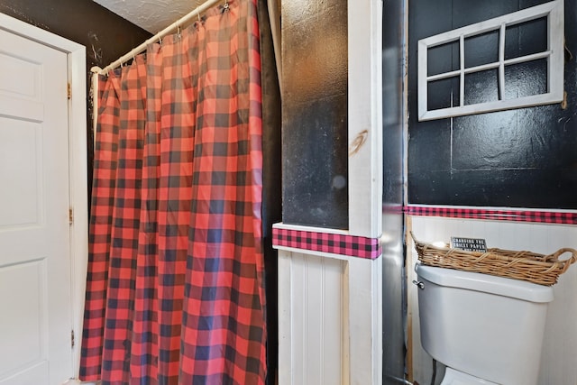 interior space featuring a shower with shower curtain and toilet