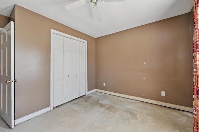 unfurnished bedroom with concrete flooring, a closet, baseboards, and ceiling fan