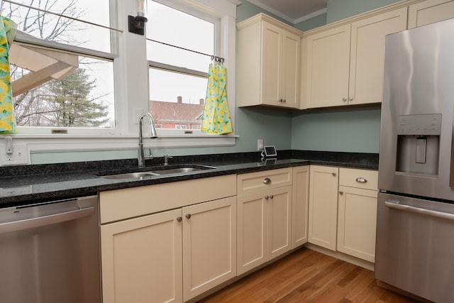 369 Ohio St, Bangor, ME 04401 - kitchen with appliances with stainless steel finishes, a sink, cream cabinetry, light wood finished floors, and dark stone counters