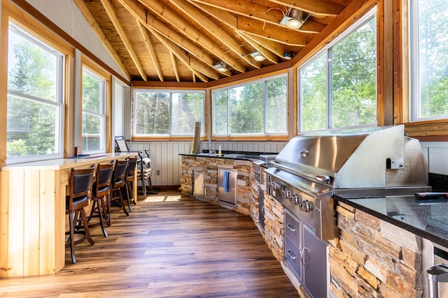 sunroom / solarium with wood finished floors and vaulted ceiling