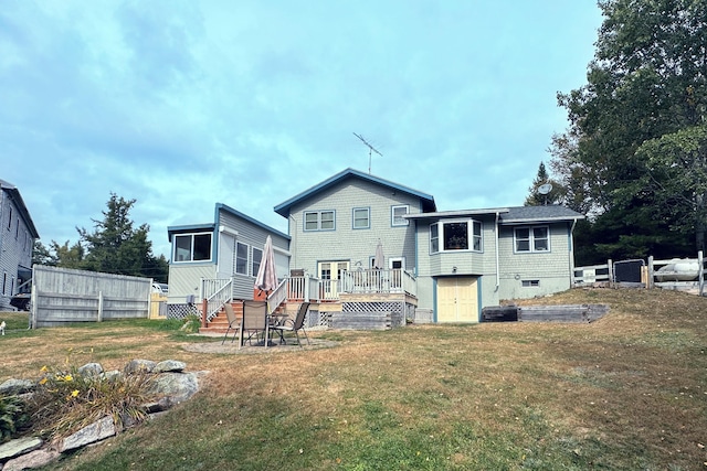 back of property featuring a yard, a wooden deck, and fence