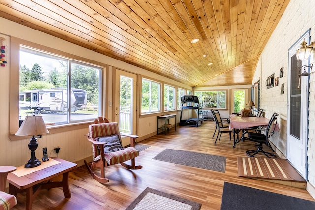 sunroom / solarium featuring lofted ceiling, wood ceiling, wood finished floors, and a healthy amount of sunlight