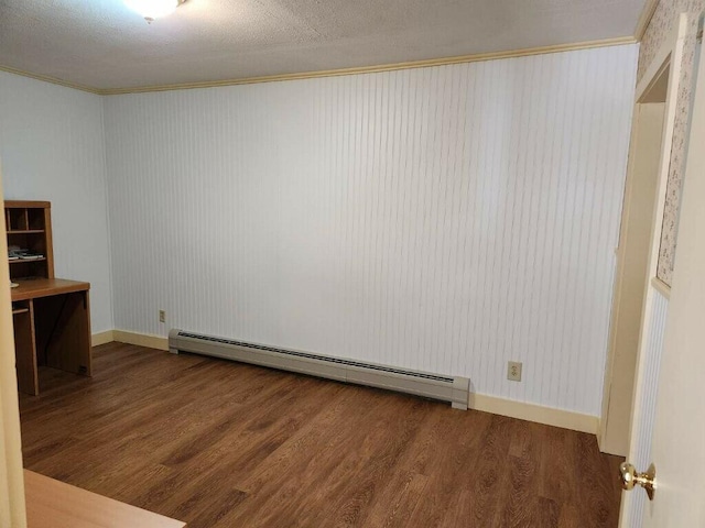 empty room with baseboard heating, crown molding, wood finished floors, and baseboards