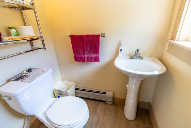 bathroom featuring a baseboard heating unit, baseboards, toilet, and wood finished floors