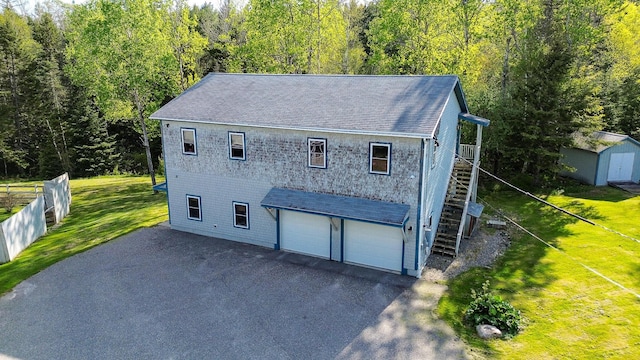 exterior space with aphalt driveway, a front lawn, and stairway