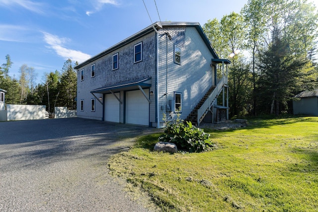 view of home's exterior featuring a garage, stairway, driveway, and a lawn