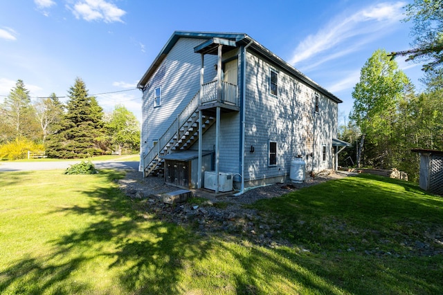 back of property with central AC, a lawn, and stairs