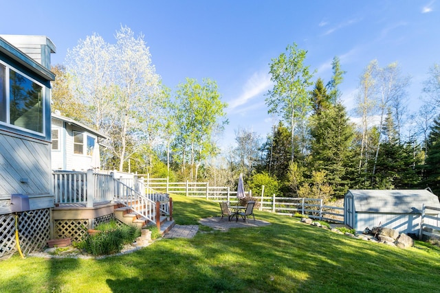 view of yard with fence private yard, a wooden deck, an outbuilding, and a storage unit