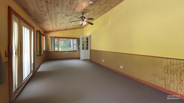 empty room featuring wooden ceiling, a ceiling fan, a wainscoted wall, carpet flooring, and lofted ceiling