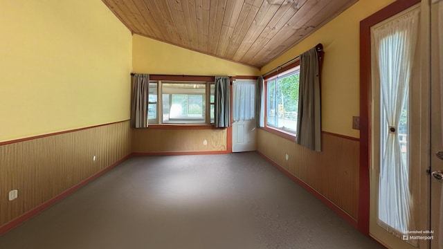 unfurnished room with wood walls, wood ceiling, wainscoting, and lofted ceiling