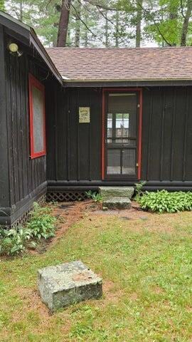 view of exterior entry with a lawn and roof with shingles