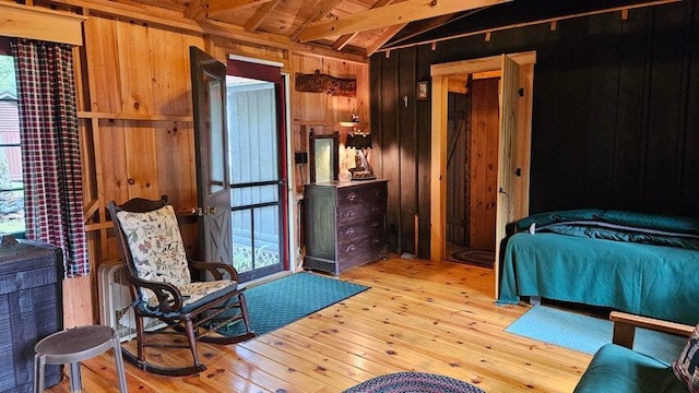 bedroom featuring wood walls, multiple windows, and light wood finished floors