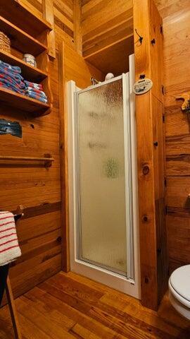 full bath with a shower stall, toilet, and wood finished floors