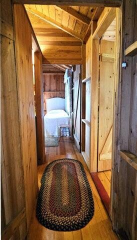 corridor featuring wood ceiling, vaulted ceiling, wood finished floors, and wooden walls