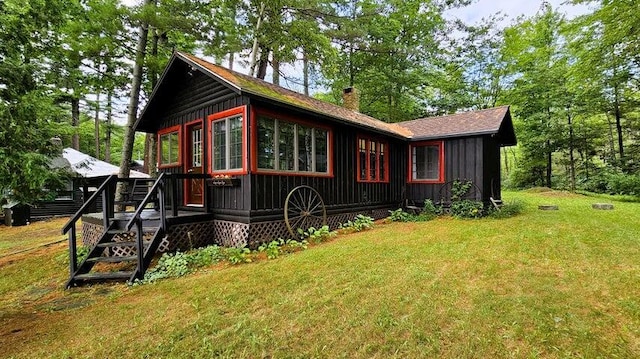 view of property exterior with a lawn, a chimney, board and batten siding, and a deck