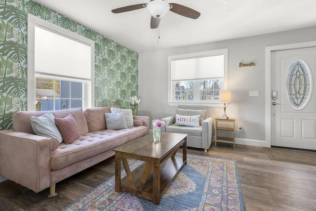living area with an accent wall, a ceiling fan, wood finished floors, wallpapered walls, and baseboards
