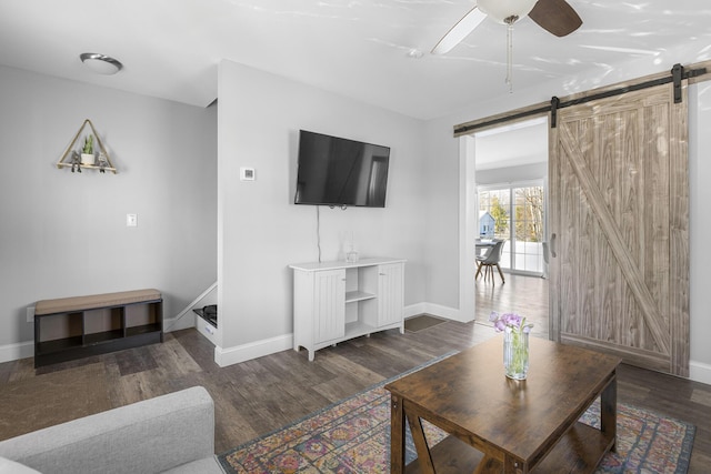 living area featuring a barn door, wood finished floors, baseboards, and ceiling fan