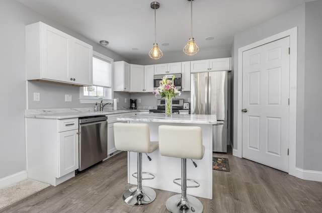 kitchen featuring white cabinets, a center island, stainless steel appliances, and a breakfast bar