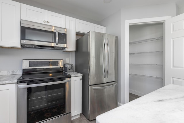 kitchen with white cabinetry, wood finished floors, and stainless steel appliances