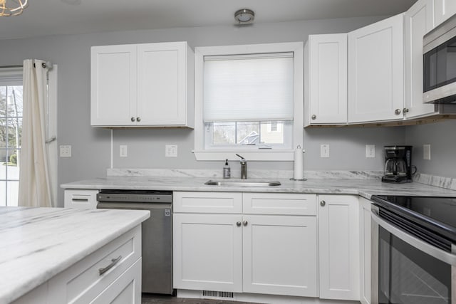 kitchen featuring white cabinetry, stainless steel appliances, a sink, and plenty of natural light