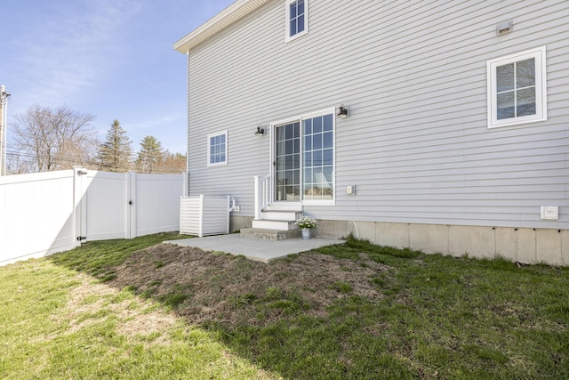 back of house featuring fence, a lawn, entry steps, and a gate