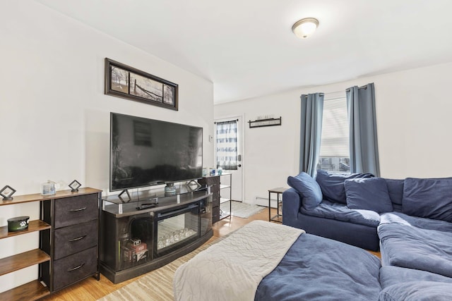 living area with baseboard heating, a wealth of natural light, and light wood-style floors