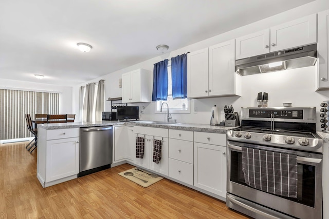 kitchen with a sink, under cabinet range hood, a peninsula, white cabinetry, and appliances with stainless steel finishes