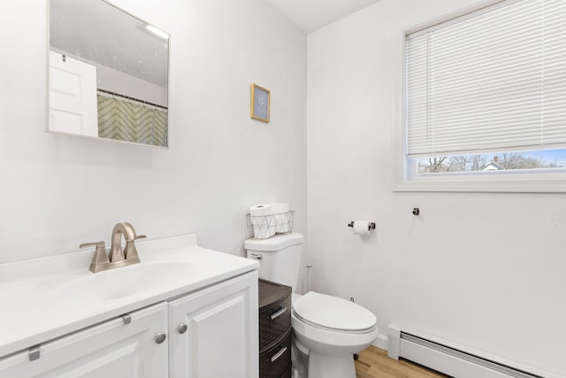 bathroom with wood finished floors, a baseboard heating unit, toilet, vanity, and baseboards