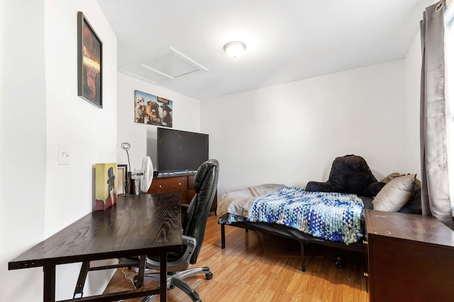 bedroom with attic access and light wood-style floors