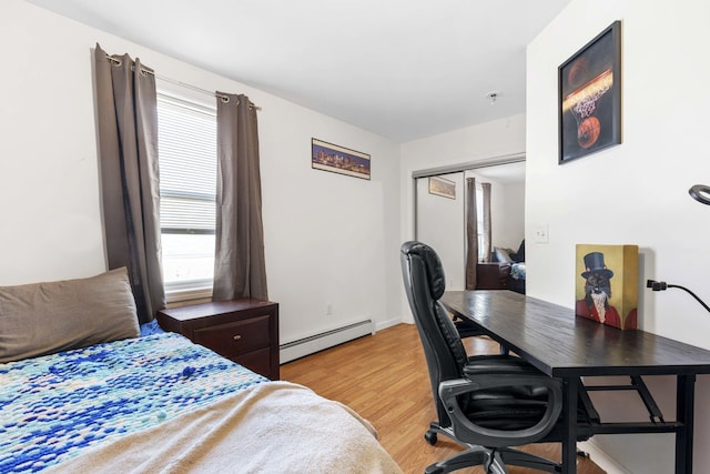 bedroom featuring a closet, light wood-style flooring, and a baseboard radiator