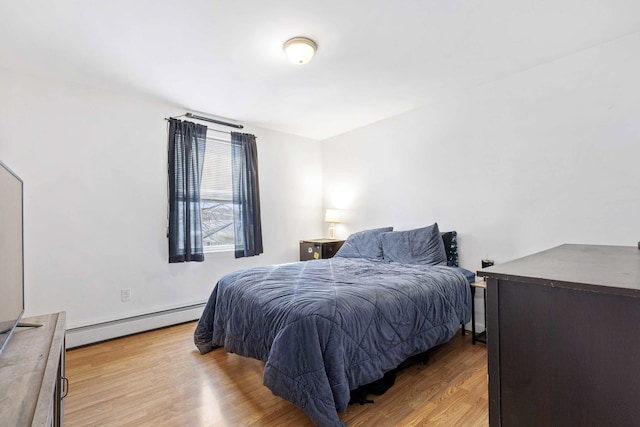 bedroom featuring baseboard heating and wood finished floors