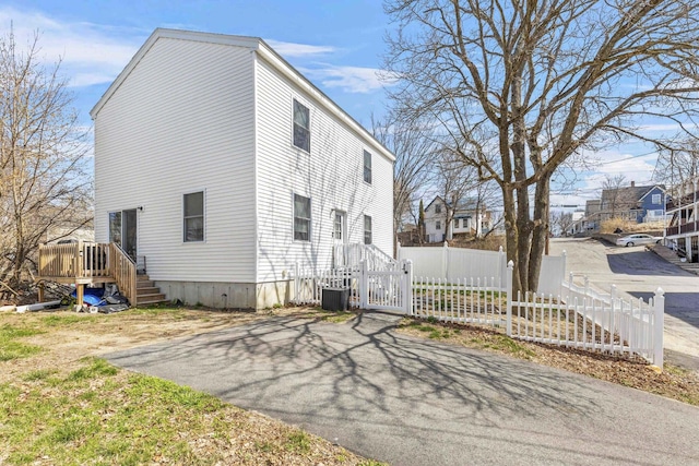 view of side of property featuring a wooden deck, driveway, and fence