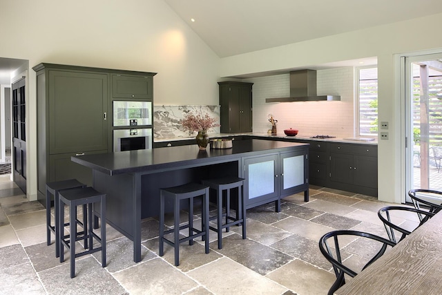 4 Ice House Pt, York, ME 03909 - kitchen with wall chimney exhaust hood, stone tile floors, backsplash, a kitchen breakfast bar, and high vaulted ceiling