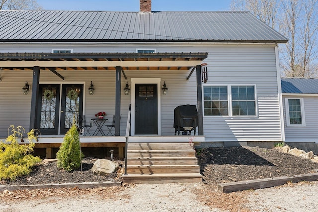 view of front facade with a porch, metal roof, and a chimney