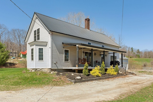 exterior space with covered porch, a lawn, a chimney, and metal roof