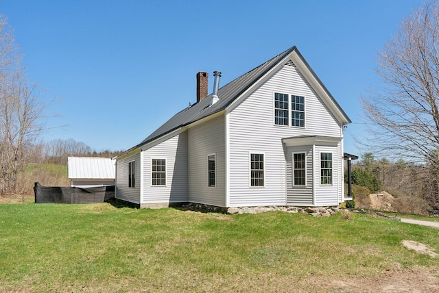 rear view of house featuring a lawn and a chimney