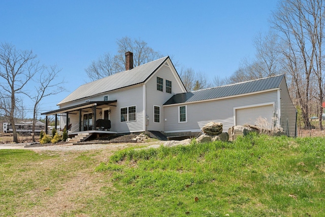 rear view of property featuring a porch, a chimney, metal roof, and a garage
