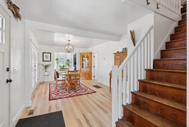 entryway with visible vents, light wood-style flooring, stairs, and baseboards