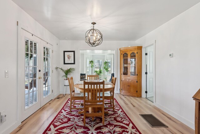 dining room with visible vents, light wood-style floors, baseboards, french doors, and a notable chandelier