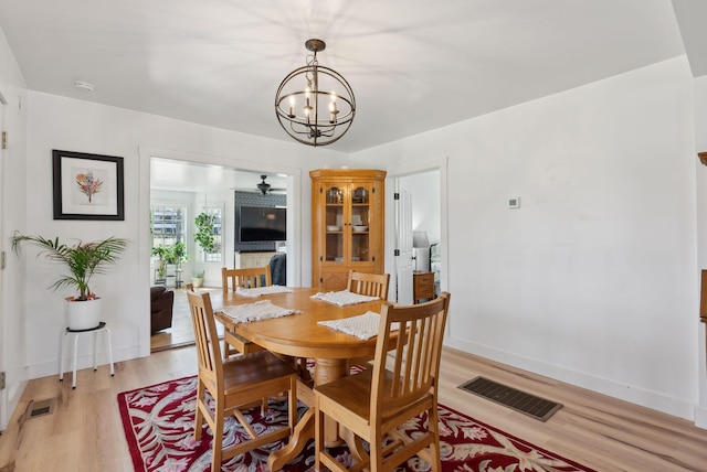 dining area with an inviting chandelier, baseboards, light wood-type flooring, and visible vents