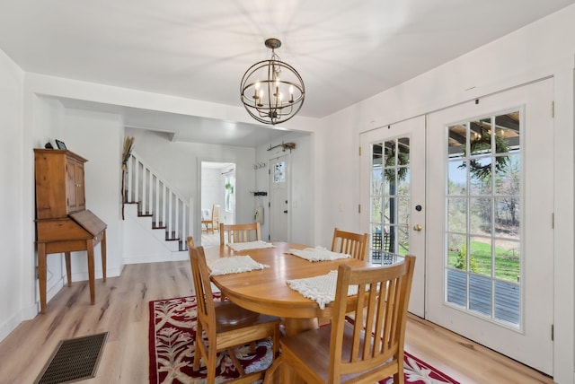 dining area with stairway, visible vents, light wood-style flooring, and an inviting chandelier