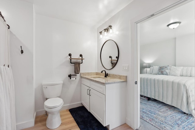 bathroom with toilet, baseboards, wood finished floors, and vanity
