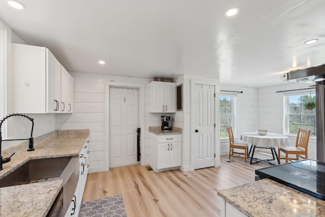 kitchen featuring light stone countertops, light wood-style floors, recessed lighting, white cabinetry, and a sink