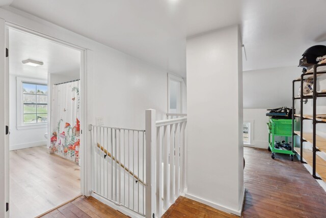 corridor with baseboards, hardwood / wood-style floors, and an upstairs landing