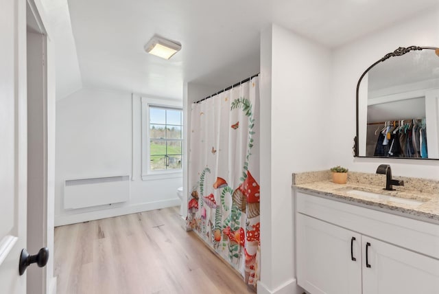 full bathroom with vanity, toilet, radiator heating unit, wood finished floors, and lofted ceiling