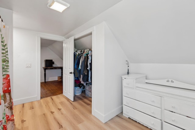 bedroom featuring a closet, baseboards, vaulted ceiling, and light wood-type flooring
