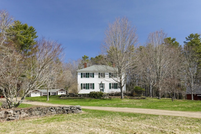 colonial inspired home with a chimney, a garage, and a front yard