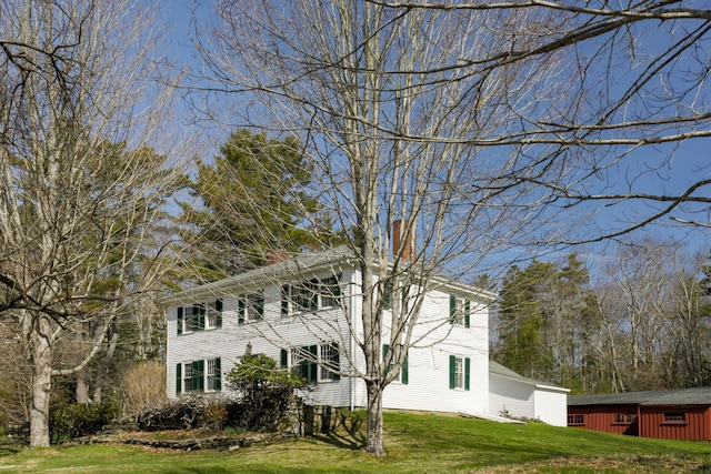 colonial home featuring a front lawn and a chimney