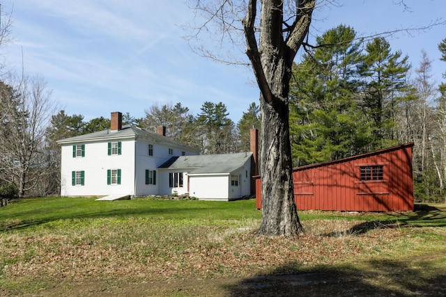back of property with a lawn and a chimney